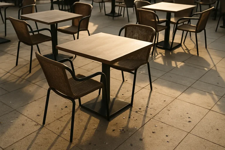 Terrasse de restaurant vide avec fientes de pigeons sur le sol, chaises et tables visibles.